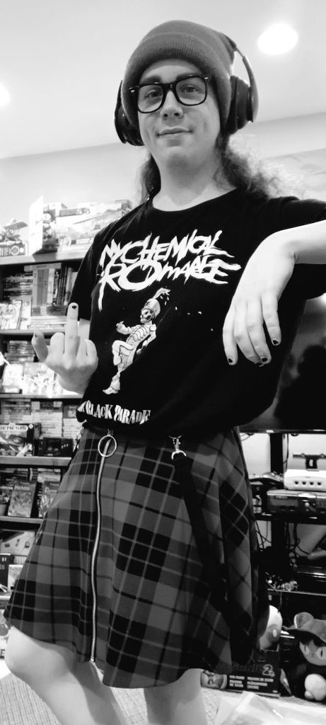 A greyscale photo of a manchild in a skirt giving a middle finger